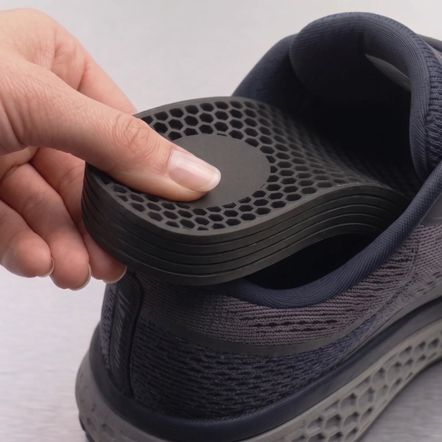 Close-up angle of the Mesa foot and heel lift system being inserted into footwear, showing the 2mm interlocking stackable layers for precise leg length discrepancy adjustment.
